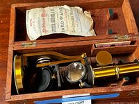 Microscope inside wooden case with paper and slides visible
