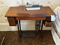 Front view of Singer wooden treadle sewing table showing drawers, top, and cast iron base