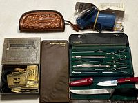 All items laid out: drafting set, stencils, coin purse, glue gun, knives, card file