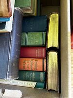 Box of assorted hardcover books with visible titles and gilt-edged volumes