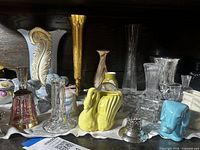 Shelf showing majority of glassware and ceramic pieces laid on white cloth