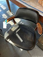 Overall view of wood and black vinyl armchair