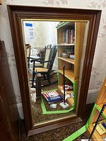 Full view of rectangular wood framed mirror leaning against wall