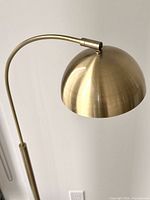 Close-up of brass dome shade and curved arm
