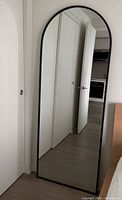 Full view of arched floor mirror leaning against wall