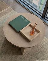 Top view of round desert-sand cast stone coffee table with book and tray for scale