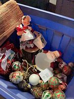 Overall view of blue bin showing Mrs. Claus figurine, Santa dish, ornaments and gift bags