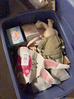 Overall view of blue storage bin containing plush bunny, boxed ceramic shakers and other Easter items