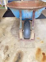 Front view showing blue tub, single rubber wheel, leg braces