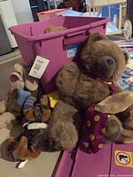 Group of plush toys leaning against purple bin