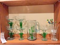Full set on shelf: five cactus glasses, cactus pitcher, Downtown Joe's glass with swizzle sticks
