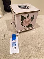 Front view showing floral design, top opening, scroll feet