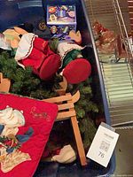 Bin with dolls, greenery, sled, box of ornaments and plates