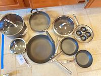 Top view of entire cookware set showing stockpot, saucepan, three skillets, egg poacher pan and lids