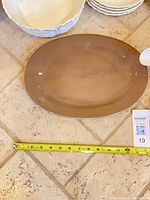 brown oval platter with tape measure indicating size