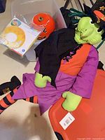 All items: plush witch, ceramic pumpkin, swim tube package, storage tote