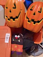 Two large plastic pumpkins and plush bat in storage bin