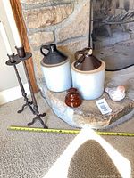 Group shot showing two stoneware jugs, brown ceramic spool piece, painted bird figurine
