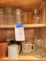 Ceramic mugs on lower shelf alongside glass mason jars