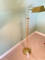 Full view of brass-tone floor lamp against wall