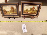 pair of framed paintings with tape measure and lot card showing scale