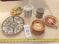Group view of plate, tea mug and divided dish with measuring tape for scale