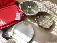 Overall lot showing baking dish in carrier, bundt pan, round cake pan, dinner plate