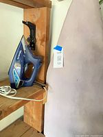 Rowenta iron resting on shelf beside ironing board