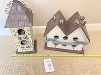 Both birdhouses side by side with measuring tape for scale