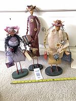 Group view of all three whimsical fabric and wood statuettes with measuring tape for scale
