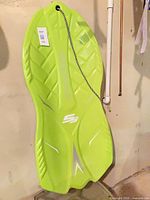Full view of green foam sled hanging, tag visible