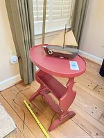 Oval painted wood side table with integrated lamp pole, cord, and decorative sailboat displayed