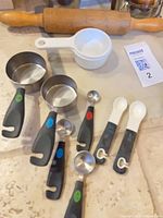 group of measuring cups, spoons and rolling pin on countertop