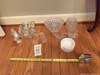 Full lot showing 13 glass pieces arranged on floor with measuring tape