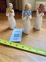 All three Willow Tree flower figurines with tape measure showing height