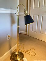 Full view of brass floor lamp against wall showing shade, column and base