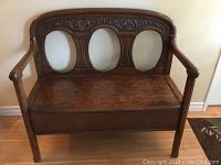 Front view of entire bench showing carved backrest, arms, and seat