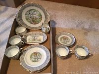 Photo showing teacups, saucers, dessert plates, and serving plate laid out on floor with Silver Birch pattern.