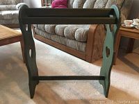 Full front and side view of the wooden quilt or blanket rack painted green, showing top bars and cutout shapes.