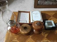 Overview photo showing the Bible in wooden box, two kerosene lanterns, wooden candleholder, salt and pepper shakers, and coaster set holder.