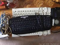 Three computer keyboards stacked, black Microsoft keyboard on top, white Future Power keyboard underneath, and a third white keyboard bottom.
