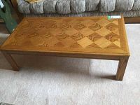 Full view of the wooden coffee table showing rectangular shape, parquet top pattern, and solid wood legs.
