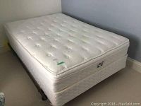 Full view of double mattress and box spring on metal frame in bedroom corner