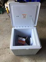 Open white Koolatron electronic cooler and warmer showing empty interior with accessories inside.