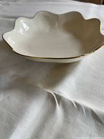 Scalloped ivory bowl with gold rim on table