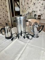 All three coffee makers on table showing relative sizes and cords