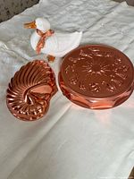 Group view of two copper molds and ceramic duck on table