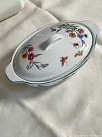 Top view of larger covered oval ceramic bowl showing floral pattern and lid handle