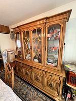 Front view of wooden china cabinet showing glass doors, drawers, hardware