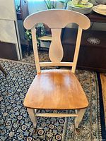 Front view of one matching chair showing white frame, natural wood seat and shaped backrest